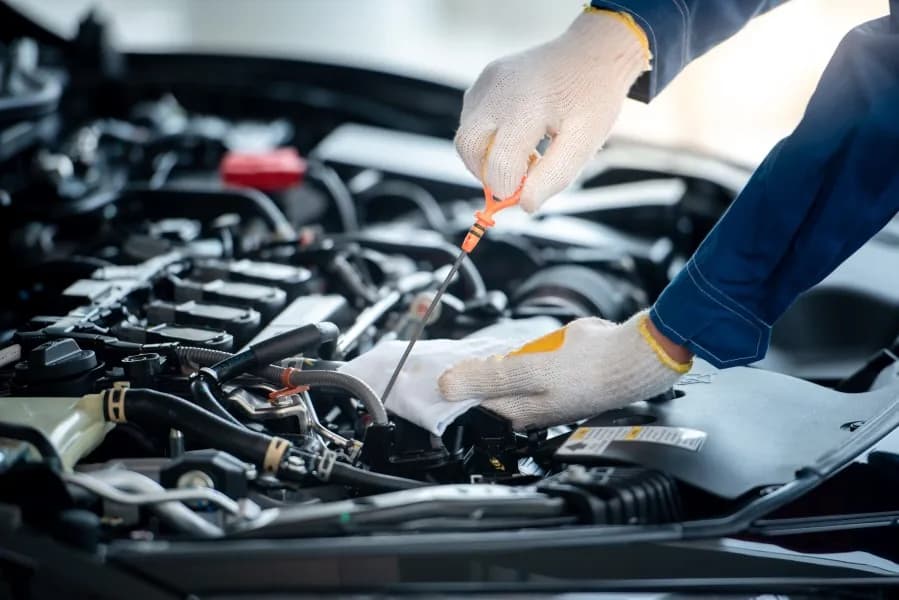 A technician in gloves checking the engine oil level with the dipstick